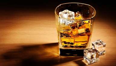 A glass of whisky with ice cubes inside