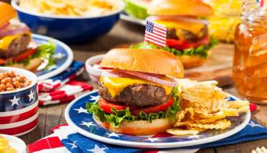 Beef burger with crisps (potato chips) and an American flag stuck in the burger bun