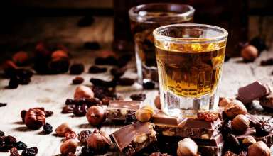 Milk chocolate and hazelnuts surrounding glasses of rum